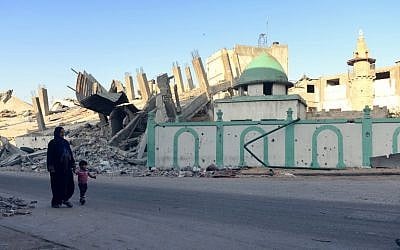 A Palestinian woman and a child walk past the destroyed Omari mosque on August 12, 2014 in Jabaliya, northern Gaza Strip. (photo credit:  AFP PHOTO/ROBERTO SCHMIDT)
