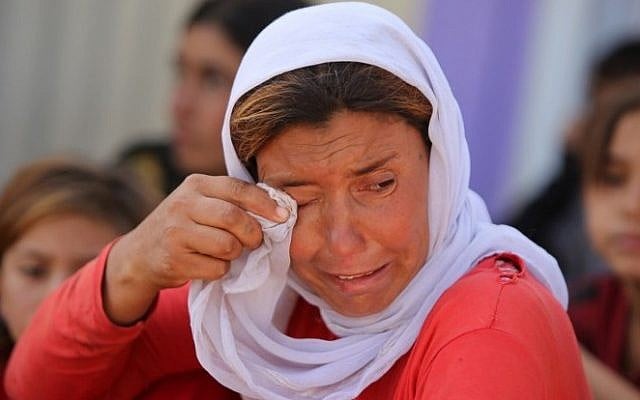 A displaced Iraqi Yazidi woman wipes her eyes at the Bajid Kandala camp near the Tigris River, in Kurdistan's western Dohuk province, where they took refuge after fleeing advances by Islamic State jihadists in Iraq on August 13, 2014. (Photo credit:AFP/AHMAD AL-RUBAYE)