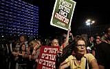 A demonstrator holds up placards reading, in Hebrew, 'When there is no peace war comes' (top) and 'Jews and Arabs refuse to be enemies' (bottom), as thousands of Israelis protest during a left-wing peace rally in Tel Aviv calling for the Israeli government to negotiate with the Palestinian Authority, on Saturday, August 16, 2014 (photo credit: AFP/GALI TIBBON)