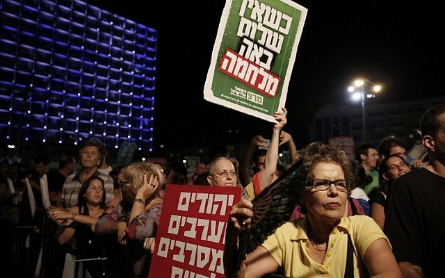 A demonstrator holds up placards reading, in Hebrew, 'When there is no peace war comes' (top) and 'Jews and Arabs refuse to be enemies' (bottom), as thousands of Israelis protest during a left-wing peace rally in Tel Aviv calling for the Israeli government to negotiate with the Palestinian Authority, on Saturday, August 16, 2014 (photo credit: AFP/GALI TIBBON) A demonstrator holds up placards reading, in Hebrew, 'When there is no peace war comes' (top) and 'Jews and Arabs refuse to be enemies' (bottom), as thousands of Israelis protest during a left-wing peace rally in Tel Aviv calling for the Israeli government to negotiate with the Palestinian Authority, on Saturday, August 16, 2014 (photo credit: AFP/GALI TIBBON)