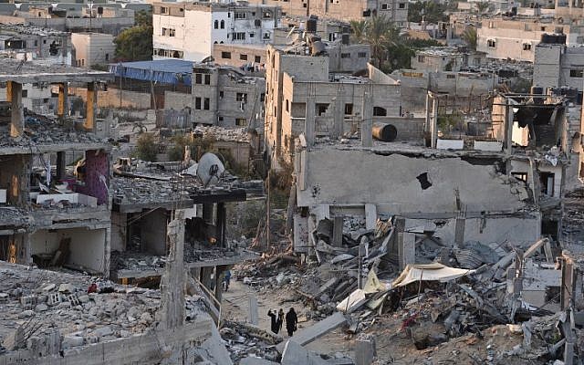 Palestinian women walk between buildings destroyed during fighting between Hamas militants and Israel in the Al-Shaas neighbourhood, in the north of the Gaza Strip, on August 16, 2014. (photo credit: AFP/ROBERTO SCHMIDT)