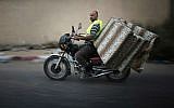 A Palestinian man drives his motorbike loaded with mattresses as he heads to a United Nations school to take refuge for the night in the northern Gaza Strip city of Beit Hanun, as a ceasefire between Israel and Hamas was due to end, on August 18, 2014. The ceasefire was later extended for another 24 hours. (photo credit: AFP/THOMAS COEX)