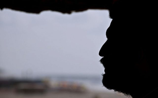 Mohammed Bar, a Palestinian man who works as a lifeguard along the beach in Gaza City looks out over the beach in a watch tower on August 18, 2014. (photo credit: AFP Photo/ Roberto Schmidt)