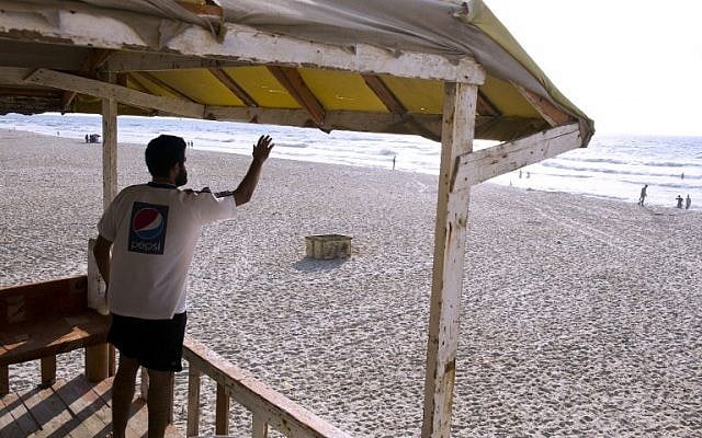 Mohammed Bar, a Palestinian man who works as a lifeguard along the beach in Gaza City gestures instructions to swimmers in sea on August 18, 2014. (photo credit:  AFP/ ROBERTO SCHMIDT)
