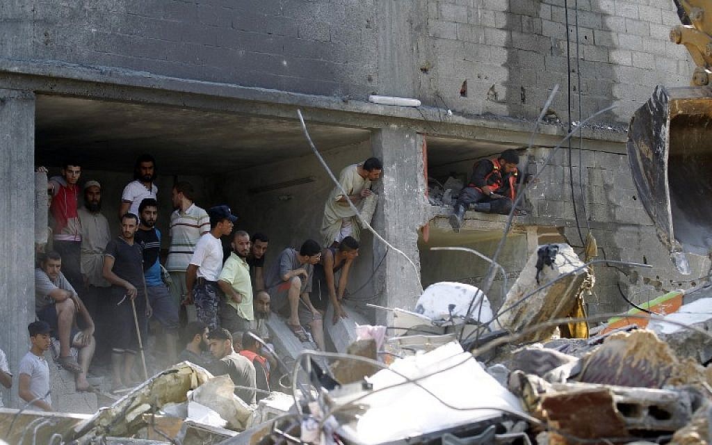 Palestinian gather around the rubble of a building destroyed following an Israeli military strike in Rafah in the south of the Gaza Strip on August 21, 2014. The armed wing of Hamas announced that three of its senior commanders were killed in a pre-dawn airstrike in southern Gaza that medics said killed seven people (photo credit: AFP/SAID KHATIB)