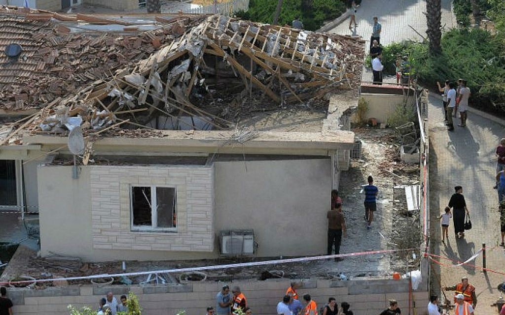 Residents and emergency services gather at the site of a damaged house in the Israeli coastal city of Ashkelon after it was hit by a rocket launched by Hamas terrorists in the Gaza Strip on August 26, 2014. (photo credit:AFP PHOTO/DAVID BUIMOVITCH)
