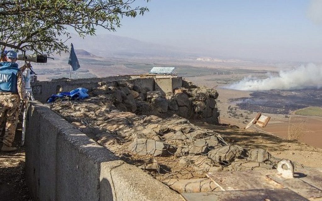 UN peacekeepers use binoculars to watch smoke rising in the distance caused by fighting between forces loyal to Syrian President Bashar Assad and rebels over the control of the Quneitra border crossing, on August 27, 2014 (Photo credit: Jack Guez/AFP)