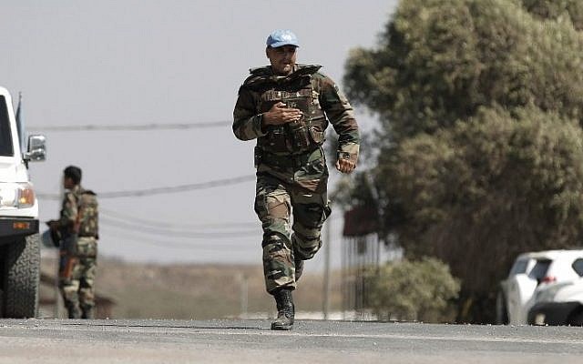 A UN peacekeeper runs past vehicles at the UN headquarters next to the Quneitra crossing, the only border crossing between Israel and Syria, in the Golan Heights on August 30, 2014 (Photo credit: Ahmad Gharabli/AFP) A UN peacekeeper runs past vehicles at the UN headquarters next to the Quneitra crossing, the only border crossing between Israel and Syria, in the Golan Heights on August 30, 2014 (Photo credit: Ahmad Gharabli/AFP)