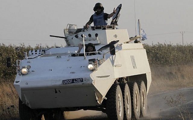 Members of the United Nations Disengagement Observer Force (UNDOF) wave as they drive their armored vehicle in the Golan Heights near the Quneitra crossing, on August 30, 2014 (photo credit: AFP/AHMAD GHARABLI)