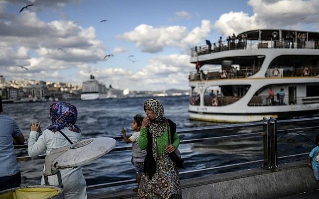 A Syrian woman (center) stands with her daughter near the Bosphorus on August 30, 2014, at Eminonu, in Istanbul. AFP Photo/Bulent Kilic) A Syrian woman (center) stands with her daughter near the Bosphorus on August 30, 2014, at Eminonu, in Istanbul. AFP Photo/Bulent Kilic)