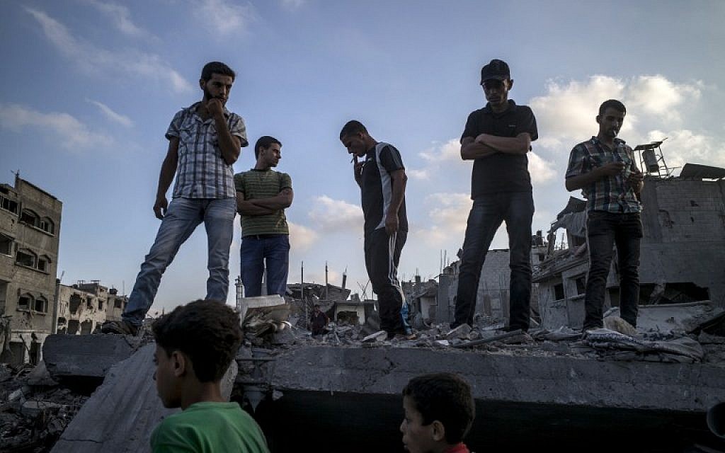 Palestinians stand on top of a destroyed building in the Gaza City neighborhood of Shejaiya, a Hamas stronghold from which hundreds of rockets have been launched at Israel, on August 6, 2014. (photo credit: AFP/MARCO LONGARI)