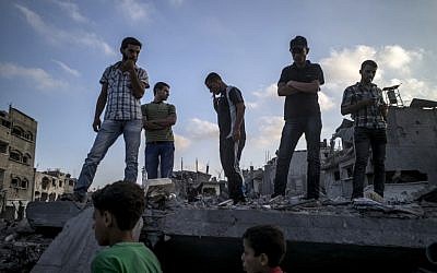 Palestinians stand on top of a destroyed building in the Gaza City neighborhood of Shejaiya, a Hamas stronghold from which hundreds of rockets have been launched at Israel, on August 6, 2014. (photo credit: AFP/MARCO LONGARI)