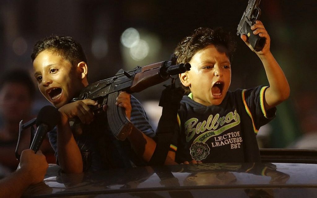 Children hold up guns (one with an empty magazine) from a car as Palestinians gather in the streets to celebrate after a deal had been reached between Hamas and Israel over a long-term end to seven weeks of fighting in the Gaza Strip on August 26, 2014 in Gaza City. (photo credit: AFP/Mohammed Abed)