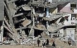 A Palestinian family walks on August 27, 2014, past the collapsed remains of a building in Shejaiya that was destroyed in fighting between Hamas and Israel. (AFP/ROBERTO SCHMIDT)