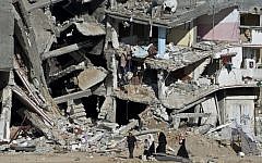 A Palestinian family walks on August 27, 2014, past the collapsed remains of a building in Shejaiya that was destroyed in fighting between Hamas and Israel. (AFP/ROBERTO SCHMIDT)
