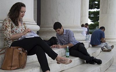 Noa Shusterman (L) and Daniel Nachum(C), Israeli students in the New Story Leadership (NSL) program, write a letter about their experiences outside the Thomas Jefferson Memorial in Washington, DC on August 1, 2014 (Photo credit: Jim Watson/AFP)