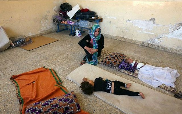 An Iraqi Yazidi mother who fled the violence in the northern Iraqi town of Sinjar, sits with her children at a school where they are taking shelter in the Kurdish city of Dohuk in Iraq's autonomous Kurdistan region, on August 5, 2014. (photo credit: AFP/SAFIN HAMED) An Iraqi Yazidi mother who fled the violence in the northern Iraqi town of Sinjar, sits with her children at a school where they are taking shelter in the Kurdish city of Dohuk in Iraq's autonomous Kurdistan region, on August 5, 2014. (photo credit: AFP/SAFIN HAMED)