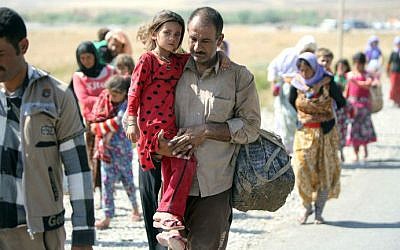 A displaced Iraqi man from the Yazidi community carries his daughter as they cross the Iraqi-Syrian border at the Fishkhabur crossing, in northern Iraq, on August 11, 2014. (AFP/Ahmad Al-Rubaye)