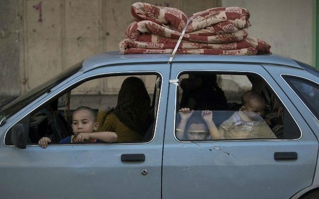 Palestinian families leave their homes in Gaza City's Shejaiya neighborhood in fear of Israeli attacks, after Palestinian factions in Gaza refused to extend the 72-hour ceasefire with Israel and opened fire on Israel, on August 8, 2014 (photo credit: AFP/ Mahmud Hams)