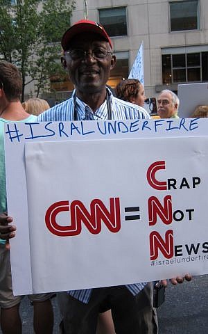 Stephen Tebid, a retired journalist, holds a sign saying 'CNN=Crap Not News' at protest in New York on August 8, 2014. (Cathryn J. Prince/The Times of Israel)
