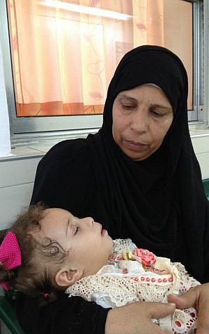 Haniyah Shaer holds her sleeping granddaughter Hala Aradha following her checkup, August 12, 2014 photo credit: Elhanan Miller/Times of Israel) 