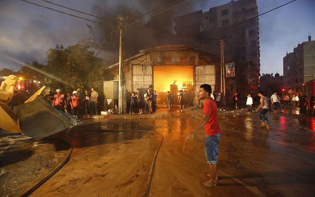 Firefighters try to extinguish fire after a cleaning materials factory was hit by an Israeli airstrike in Gaza City on Sunday, Aug. 10, 2014. (Photo credit: AP/Hatem Moussa)