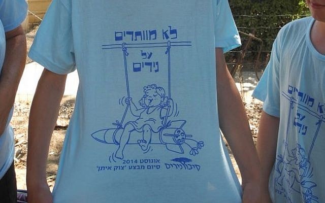 Regev Haglili shows off a shirt made in honor of the residents return over the weekend, which says "Were not giving up on NIrim" in Hebrew. (photo credit: Melanie Lidman/Times of Israel)