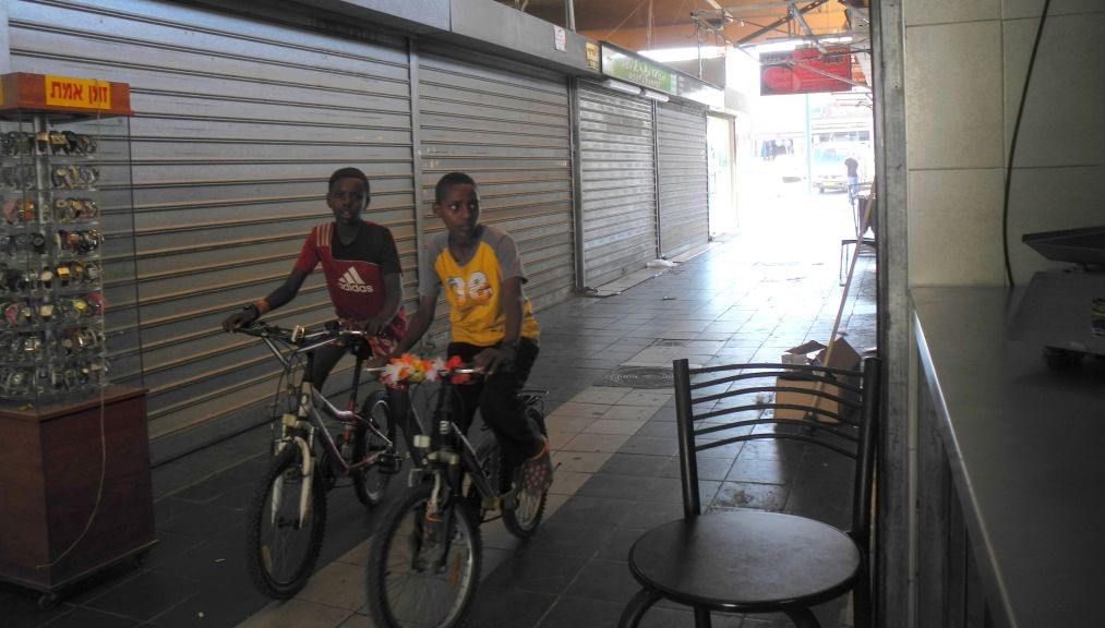 Children in Sderot ride their bikes through a mostly empty shuk on Wednesday afternoon. (photo credit: Melanie Lidman/Times of Israel)