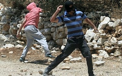 Illustrative photo of masked Palestinians throwing stones in the West Bank,  June 28, 2013. (photo credit: Issam Rimawi/Flash90)