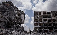 Palestinians walk in front of buildings destroyed by the Israeli military in the northern Gaza Strip town of Beit Lahiya, Monday, August 4, 2014. (Emad Nasser/Flash90)
