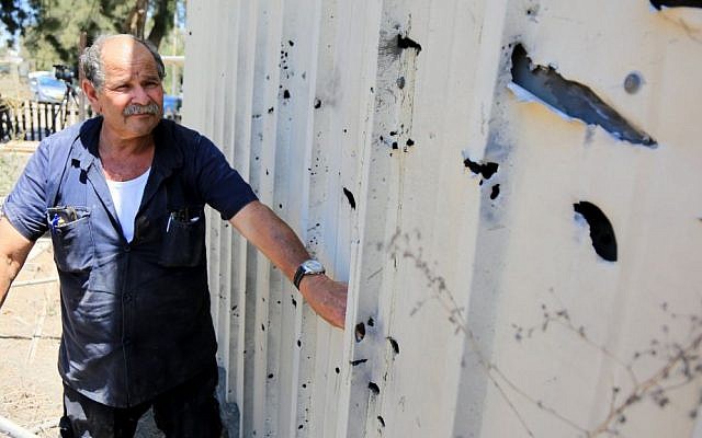 A man inspects the damage caused by a rocket that exploded near Israel's border with the Gaza Strip on Friday, August 8, 2014. (photo credit: Edi Israel/Flash90)
