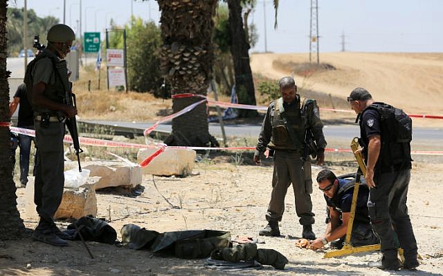 Police sappers inspect a part of a rocket that had exploded and fallen near the border with the Gaza Strip on August 8, 2014.(photo credit: Edi Israel/Flash90)