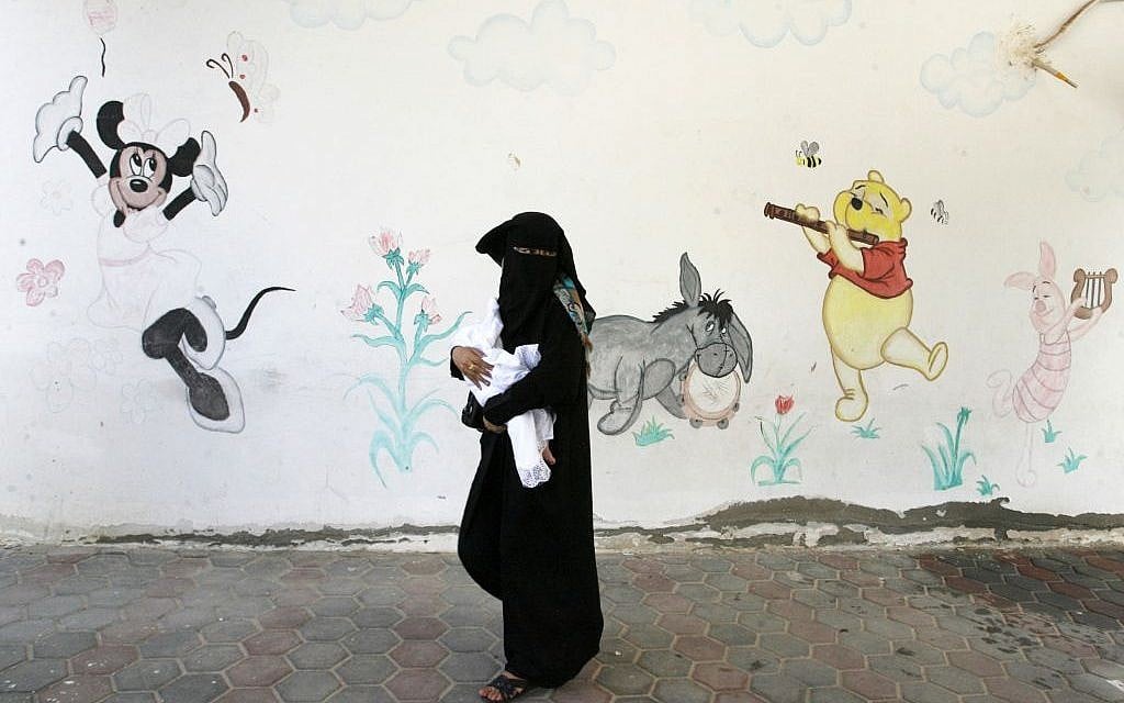 A Palestinian woman holds her baby, who war born in a shelter during the Israeli offensive, during a ceremony to honor the mothers in an UNRWA center in Rafah refugee camp, in the southern Gaza Strip on Wednesday, August 13, 2014 (photo credit: Abed Rahim Khatib/Flash90)