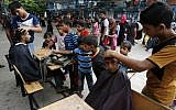 Palestinians get hair cuts at an UNRWA school in Rafah where they took shelter during the Gaza war, on August 17, 2014 (Abed Rahim Khatib/Flash90)