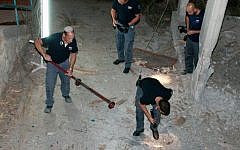 Israeli bomb squad police officers seen collecting the remains of a rocket fired from southern Lebanon into Israel, landing in the western Galilee, northern Israel. August 23, 2014. (photo credit: Ayal Margolin/Flash90)