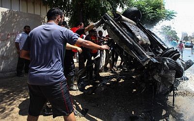 Palestinians around a destroyed vehicle after an Israeli airstrike in Gaza City on August 24, 2014. (photo credit: Emad Nassar/Flash90) Palestinians around a destroyed vehicle after an Israeli airstrike in Gaza City on August 24, 2014. (photo credit: Emad Nassar/Flash90)