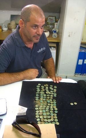 IAA archaeologist Pablo Betzer at the laboratories in Jerusalem's Har Hotzvim, with Jewish Revolt coins set out in front of him. (photo credit: Ilan Ben Zion/Times of Israel staff)