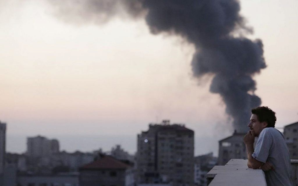This photo, taken in August 2014, shows Associated Press video journalist Simone Camilli on a balcony overlooking smoke from Israeli Strikes in Gaza City. Camilli was killed on August 13 when working to document an attempt to defuse an Israeli leftover missile in Gaza. (AP Photo/Lefteris Pitarakis)