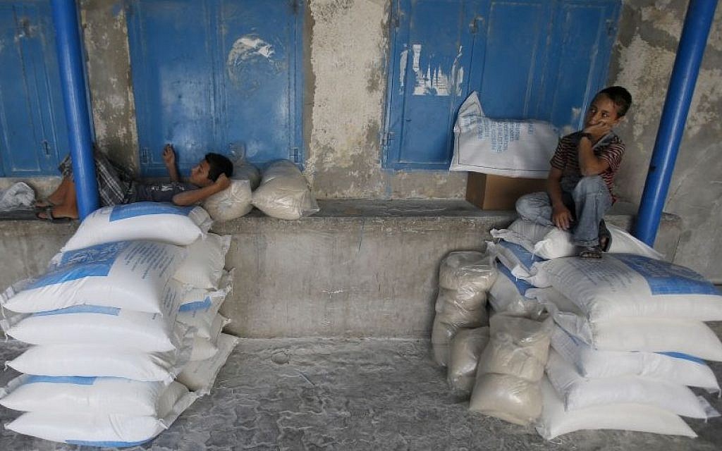A Palestinian boy sits on bags of flour at a United Nations food aid distribution center, in the Shati refugee camp in Gaza City, Wednesday, Aug. 6, 2014. (Photo credit: AP/Hatem Moussa)