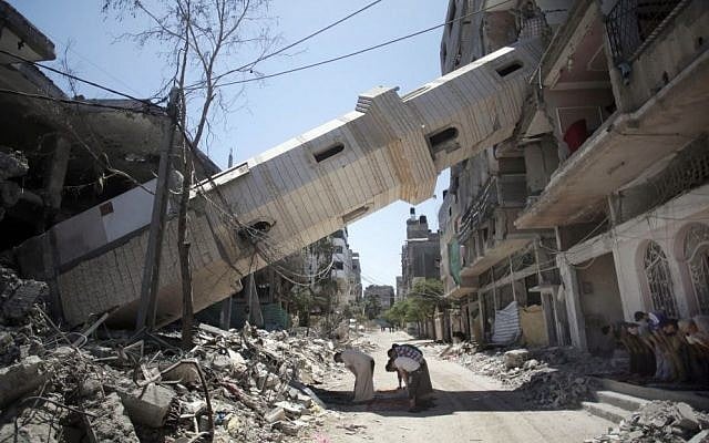 Palestinians attend Friday noon prayers in the shadow of a toppled minaret at a mosque that was hit by Israeli strikes, in Gaza City, Friday, Aug. 8, 2014. Hamas ended a truce Friday morning and resumed firing rockets into Israel, drawing Israel air strikes on what Israel said were terror targets. Israel says rockets and tunnels have been sited in Gaza schools, mosques and homes. (photo credit: AP/Khalil Hamra)