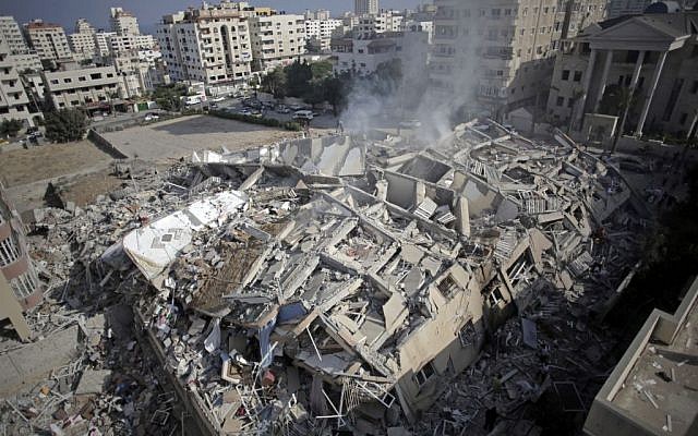 Smoke rises from the rubble of the al-Zafer apartment tower following Israeli airstrikes Saturday that collapsed the 12-story building, in Gaza City, Sunday, August 24, 2014. (photo credit: AP/Khalil Hamra)
