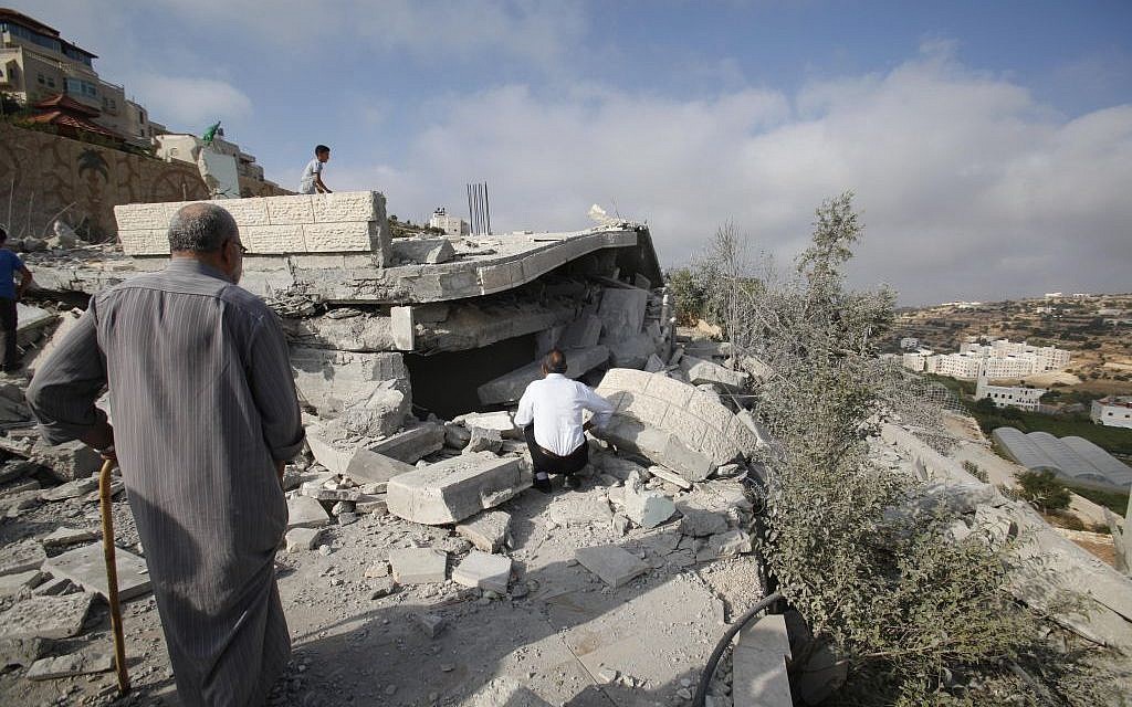 Palestinians inspect the rubble of the house of Hussam Kawasme, one of three Palestinians identified by Israel as suspects in the killing of three Israeli teenagers, after it was demolished by the Israeli army in the West Bank city of Hebron, Monday, Aug. 18 , 2014. (photo credit: AP/Nasser Shiyoukhi)