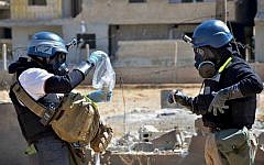 Investigators take samples from sand near a part of a missile that was suspected of carrying chemical agents, according to activists, in the countryside of Ain Terma, Syria, August 28, 2013. (AP/United Media Office of Arbeen, File)