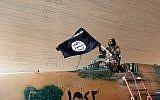A Fighter of the Islamic State group waving their flag from inside a captured government fighter jet following the battle for the Tabqa air base, in Raqqa, Syria in August, 2014. (photo credit: AP/Raqqa Media Center of the Islamic State group)