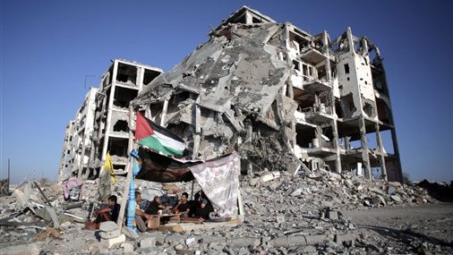 In this Monday, Aug. 11, 2014 file photo, Palestinian Ziad Rizk, sits with others in a shelter made of a blanket stretched over four poles next to one of the destroyed al-Nada Towers, where he lost his apartment and clothes shop, in the town of Beit Lahiya, northern Gaza Strip. (photo credit: AP Photo/Khalil Hamra, File) In this Monday, Aug. 11, 2014 file photo, Palestinian Ziad Rizk, sits with others in a shelter made of a blanket stretched over four poles next to one of the destroyed al-Nada Towers, where he lost his apartment and clothes shop, in the town of Beit Lahiya, northern Gaza Strip. (photo credit: AP Photo/Khalil Hamra, File)