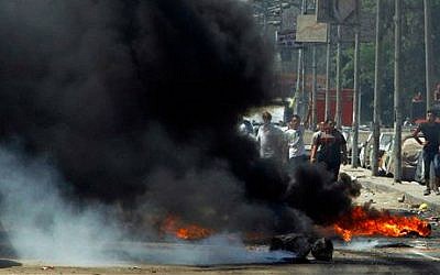 Supporters of Egypt's ousted President Mohammed Morsi stand behind smoke from burning debris set ablaze during clashes with security forces on a street in the Matariya neighborhood of Cairo, Egypt, Friday, Aug. 15, 2014  (photo credit: AP/Ahmed Abdel Fattah, El Shorouk Newspaper)