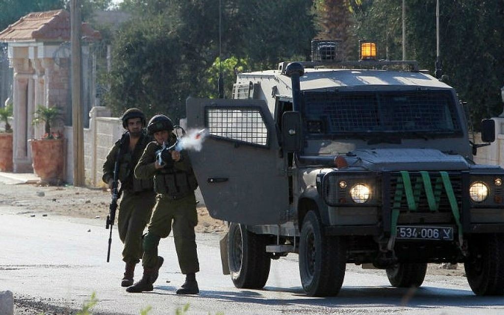An Israeli soldier fires tear gas towards Palestinians during clashes following a protest against Israel's military offensive in the Gaza Strip on August 15, 2014 in the West Bank village of Silwad, near Ramallah (AFP/ Abbas Momani)