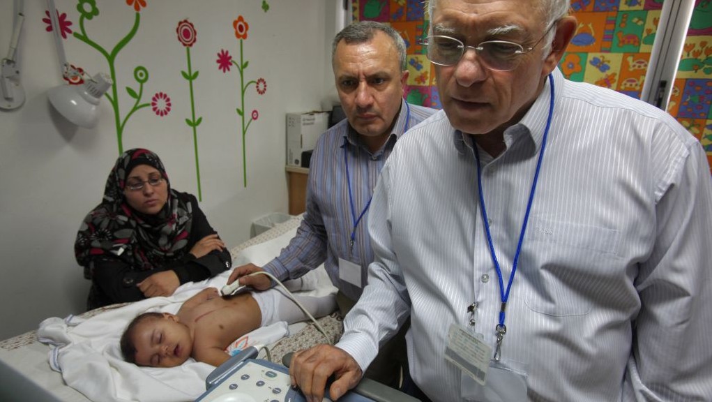 Paediatric cardiologists Dr. Akiva Tamir, of Wolfson Medical Center, and Dr. Omar Assali, of Nablus's Rafidiya hospital, preform a follow-up echo-cardiograph examination together on a Palestinian patient at Wolfson hospitals clinic photo credit: David Silverman/Flash90)