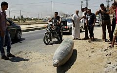 Palestinians look at an unexploded munition on a street in Deir El-Balah in the central Gaza Strip on August 01, 2014. (photo credit: Mostafa Ashqar/FLASH90)