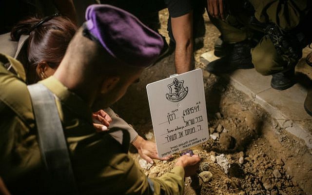 Relatives and friends seen mourning over the grave of Major Benaya Sarel, during his funeral at the old Jewish cemetery in Hebron on August 3, 2014. (photo credit: Flash90) 